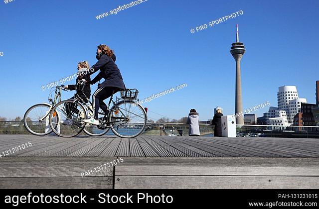 firo: 24.03.2020, Germany, NRW, Dusseldorf, Society, two people in the Medienhafen and two bicycle riders Dusseldorf, in the background the Rheinturm and the...