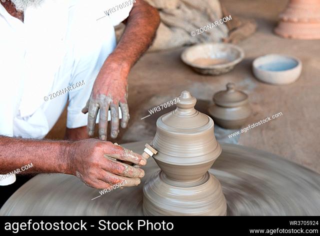 Senior man making handmade clay pottery with bare hands on the potter wheel. India handicrafts