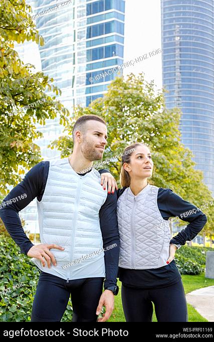 Male and female athlete standing with hands on hips at park