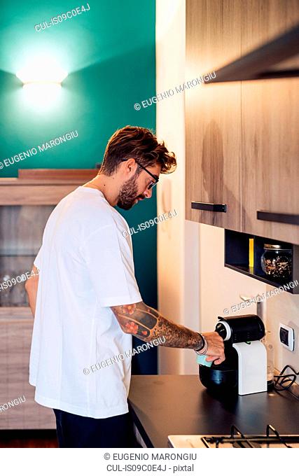 Mid adult man pouring coffee from coffee machine on kitchen counter