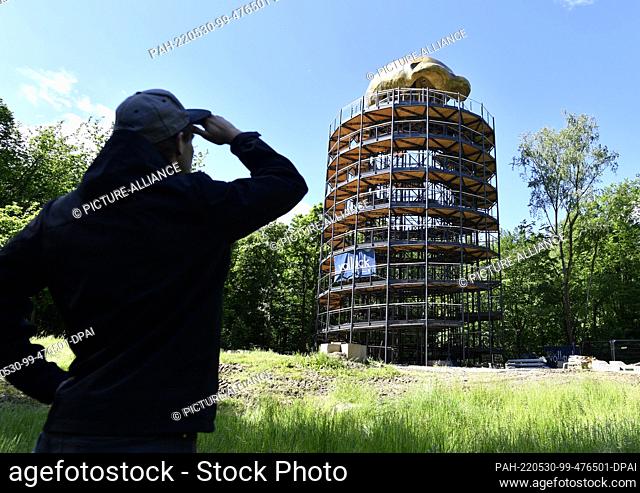 25 May 2022, North Rhine-Westphalia, Mettmann: A man looks in the distance at a roof structure modeled after the skull calotte of the prehistoric man's skull
