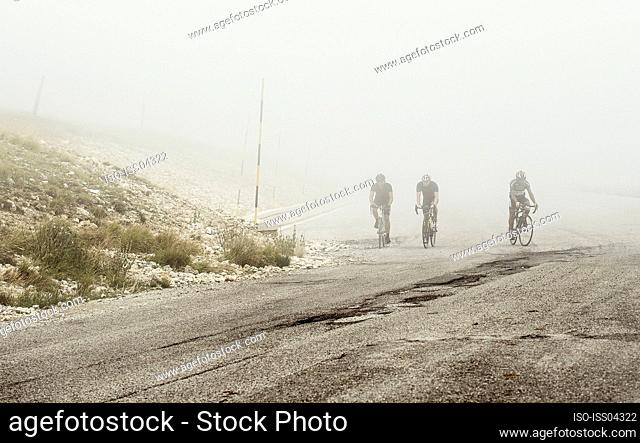 Cyclists under fog in Pretoro, Italy