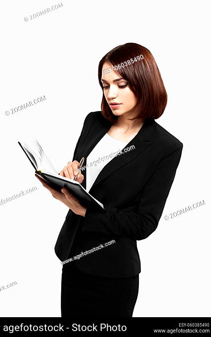 Business woman holding in hands daily, isolated on white background with clipping path. She is writing in her organizer, makes notes in notebook