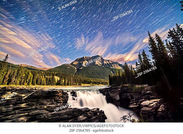 The stars of autumn rising over Mount Kerkeslin and Athabasca Falls in Jasper National Park, Alberta, on a night with a waxing quarter Moon illuminating the...