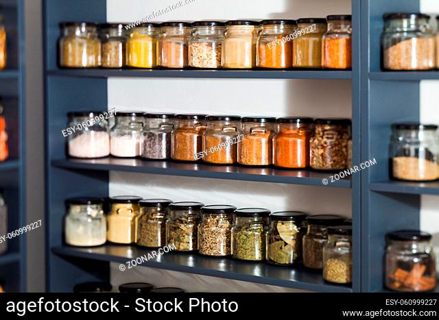 Shelf in a shop with colorful natural spices and powders in glass jars on display. Dry fruits and nuts, cereals in the shop