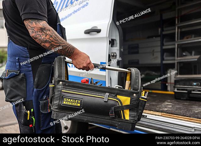 28 June 2023, North Rhine-Westphalia, Cologne: A craftsman takes a bag with tools out of a vehicle. Tools have been stolen from tradesmen's vehicles in North...