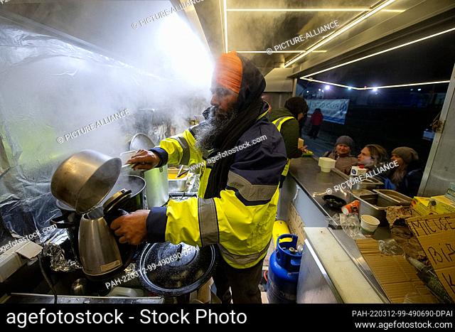 11 March 2022, Poland, Medyka: Balwant Singh fills water into a stove in the ""India Food Truck"" of the United Sikhs organization shortly after the border...