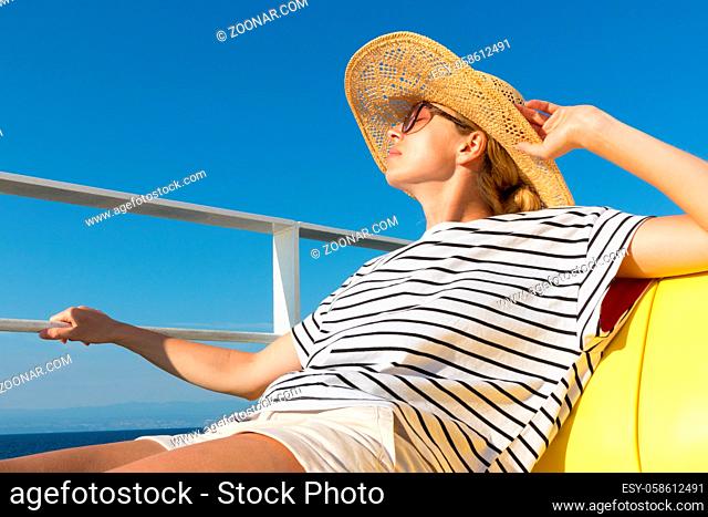 Beautiful, romantic blonde woman relaxeing on summer vacations traveling by cruse ship ferry boat. Summer vacation lifestyle