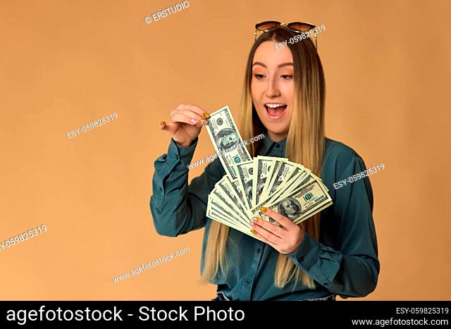shocked young woman holds cash money in dollar banknotes. copy space. focus on money