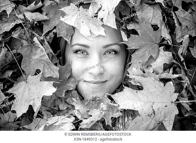 Blonde haired woman outdoors in leaf pile