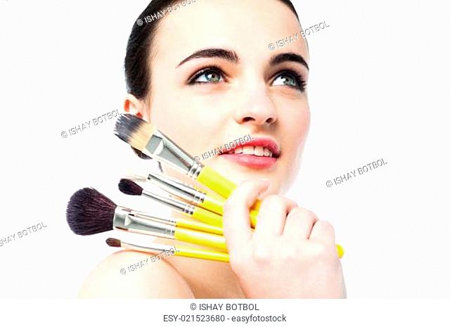 Beautiful teen girl holding makeup brushes