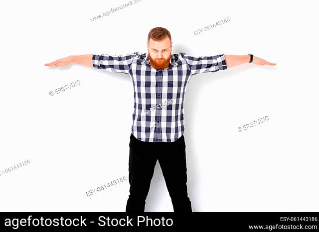 handsome man with beard pointing copy space. young man in plaid shirt showing large size of something under his arms