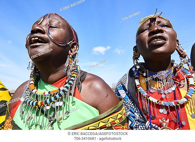 Group of Massai women singing and dancing in traditional dress and adorned with bead work, Masai Mara National Reserve, Kenya