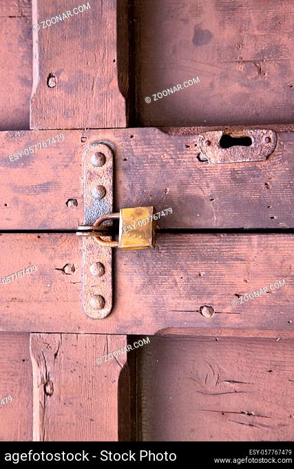 abstract padlock rusty brass brown knocker in a  closed wood door crenna gallarate varese italy