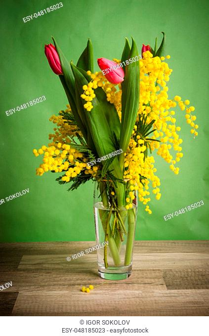 Spring bouquet with mimosa and tulips in a vase
