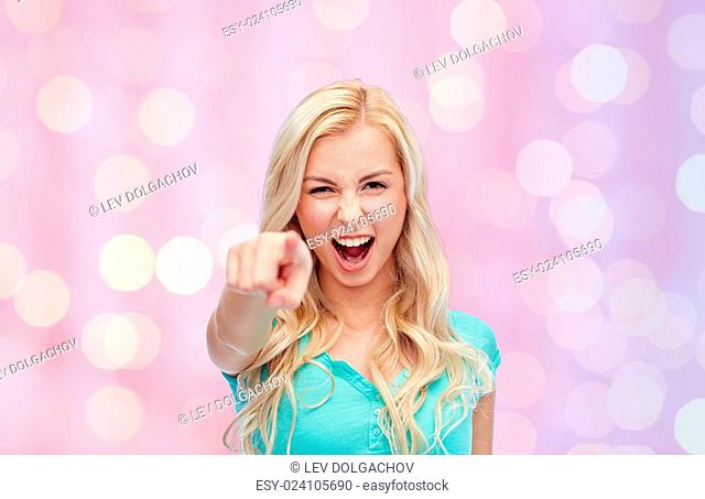 gesture, emotions, expressions and people concept - happy smiling young woman or teenage girl pointing finger to you over pink holidays lights background