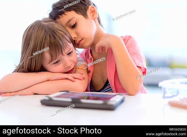 cute little brother and sister having fun at home childrends playing games on tablet computer