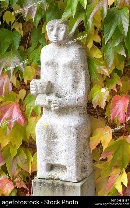 Stone statue in front of colored leaves