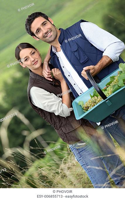 Farmer couple in field with basket of grapes