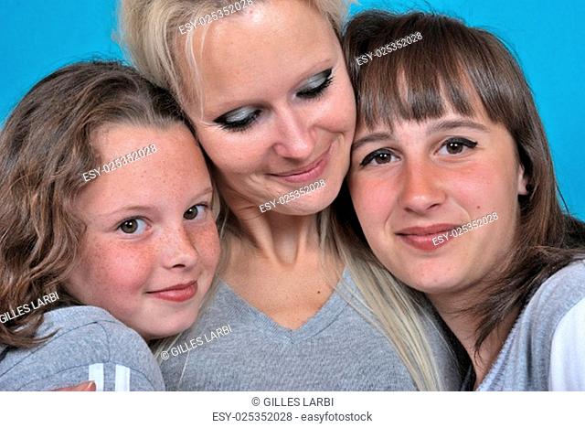 A mother smiles as she receives a kiss on the cheek from her young daughters