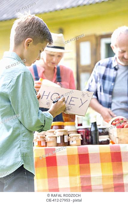 Boy drawing honey sign for farmer’s market stall