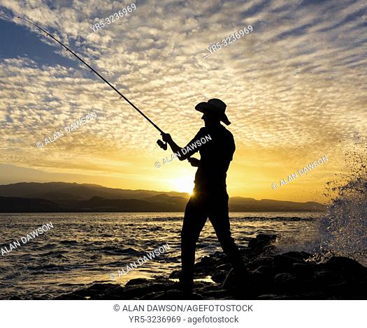 Las Palmas, Gran Canaria, Canary Islands, Spain. Man fishing on the north coast of Gran Canaria at sunset. Model released