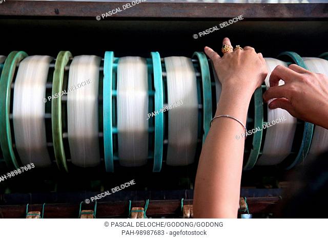 Traditional silk factory. Woman working on silk spinning machine. Dalat. Vietnam. | usage worldwide. - Dalat/Lam Dong/Vietnam