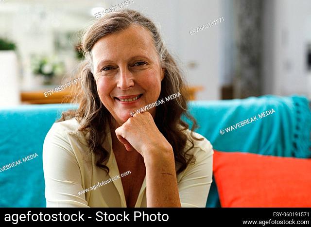 Portrait of happy senior caucasian woman in living room sitting on sofa, looking to camera