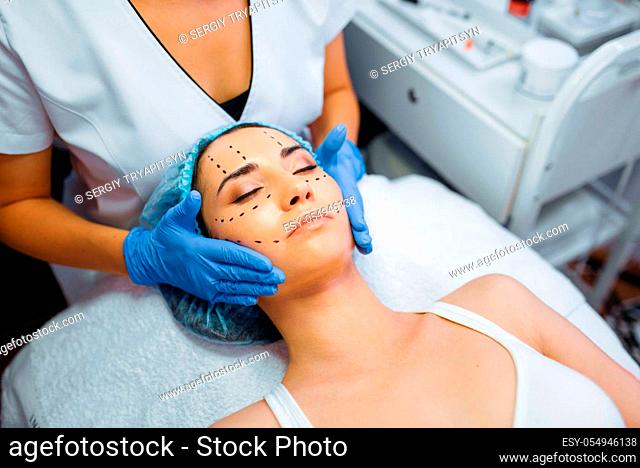 Cosmetician makes botox injection in dotted lines on female patient face, botox injections preparation. Rejuvenation procedure in beautician salon