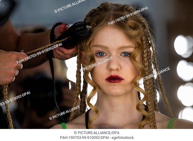 03 July 2019, Berlin: A model gets her hair styled by designer Lena Hoschek before the show. The collections for Spring/Summer 2019 will be presented at Berlin...