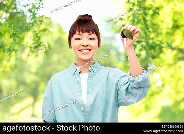 happy asian woman holding car key with green leaf