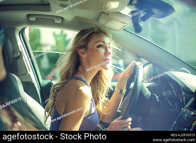 Blond woman looking out while driving with friend during road trip
