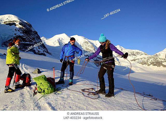 Three mountaineers preparing a roping party, Cambrena glacier, ascent to Piz Palue, Grisons, Switzerland