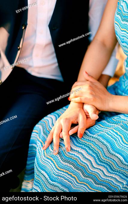 Man in a suit and woman in a striped blue dress are sitting holding hands. High quality photo