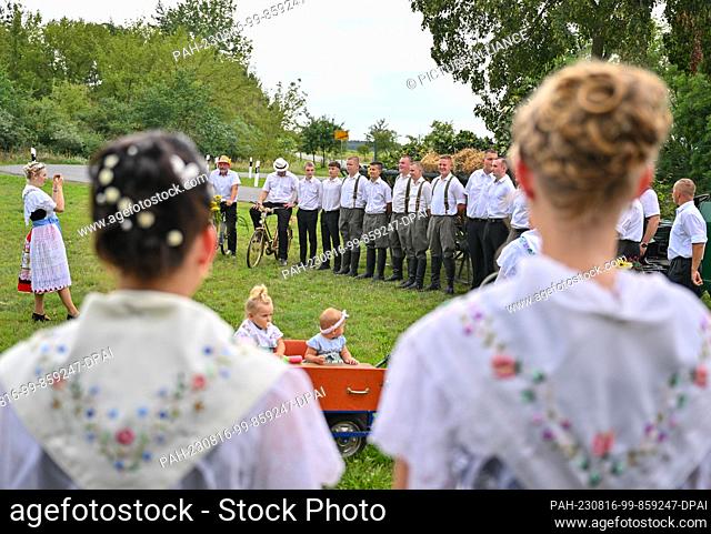 12 August 2023, Brandenburg, Heinersbrück: Young men and young women in Sorbian-Wendish festive costumes take part in the parade of the village and harvest...