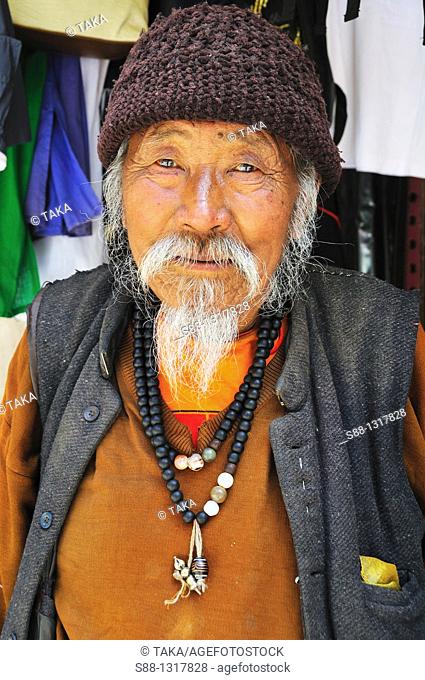 Tibetan old man selling things from Tibet on the main street where do not have any traffic, Himachal Pradesh India
