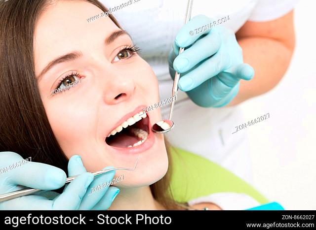Close-up picture of young woman sitting in the dentist#39;s chair with opened mouth at dentist#39;s office while having examination