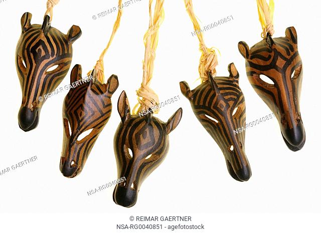 Five carved zebra heads dangling from cord on a white background