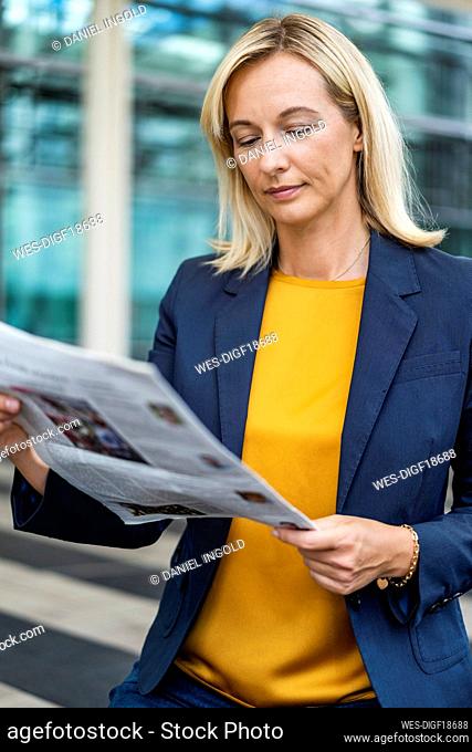 Mature blond businesswoman reading newspaper