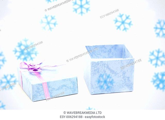 Snowflakes against open blue gift box with purple ribbon