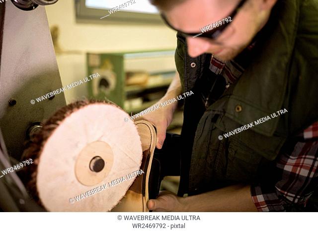 Cobbler using a machine on a shoe sole in a workshop