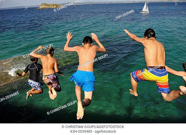 teenagers diving from the top of a sea wall at Treboul, Douarnenez, Finistere department, Brittany region, west of France, western Europe