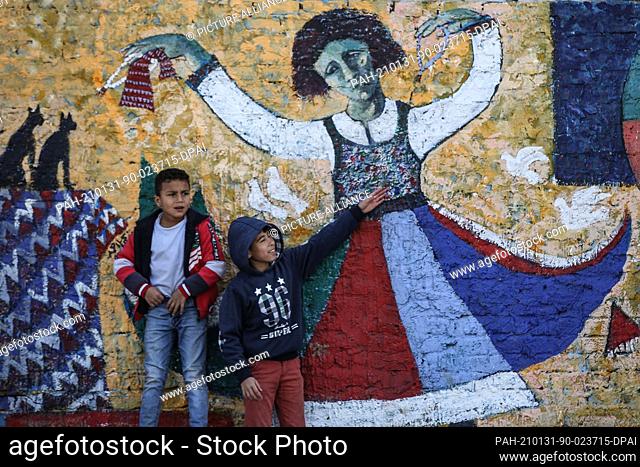 30 January 2021, Egypt, Burullus: Children play in front of a mural, painted on a local house, in the Nile Delta town of Burullus in the city of Kafr el-Sheikh
