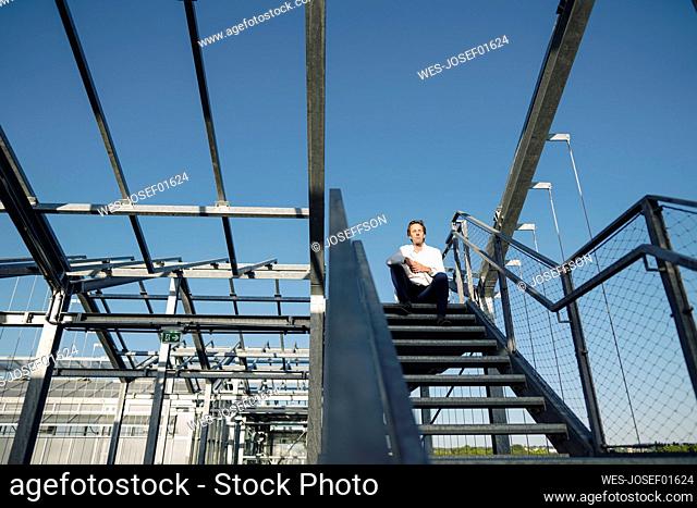 Scientist sitting on stairs under blue sky