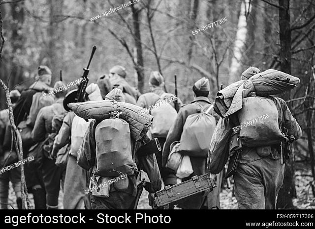 Re-enactors Dressed As World War II Russian Soviet Red Army Soldiers Marching Through Forest In Autumn Day. Photo In Black And White Colors