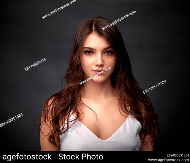 Dramatic portrait of a beautiful lonely girl on a dark background in studio