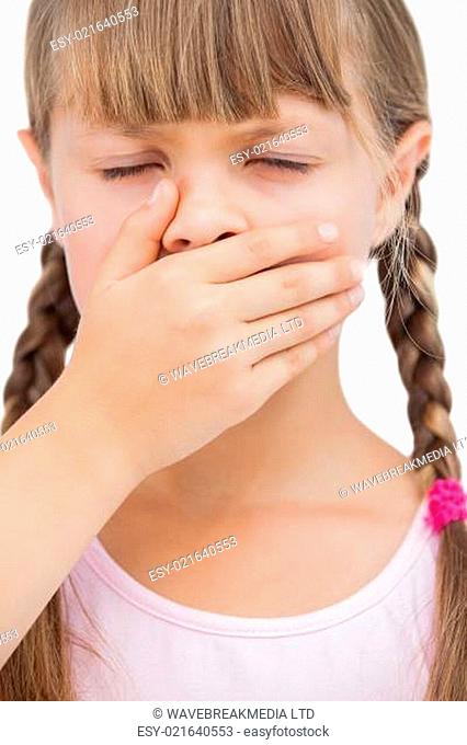 Little blond girl with her hand on her mouth with her eyes closed