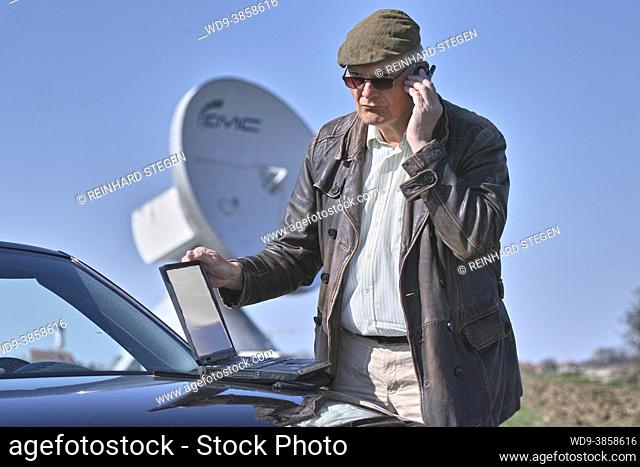Man with notebook entering data, satellite parabollic connection in the background