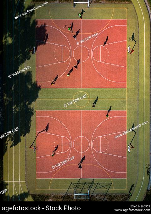Aerial view of a soccer pitch with people playing soccer on it - in warm morning sun, casting long shadows
