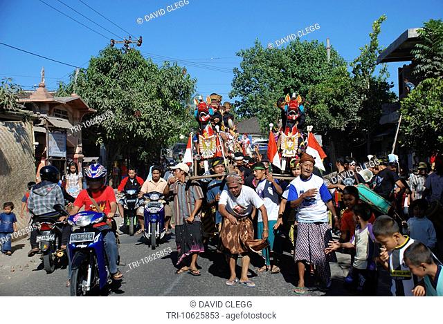 Elderly men lead the parade of boys riding ornately carved and painted wooden horses and carried aloft by vllage men in Muslim circumcision ceremony Selong...
